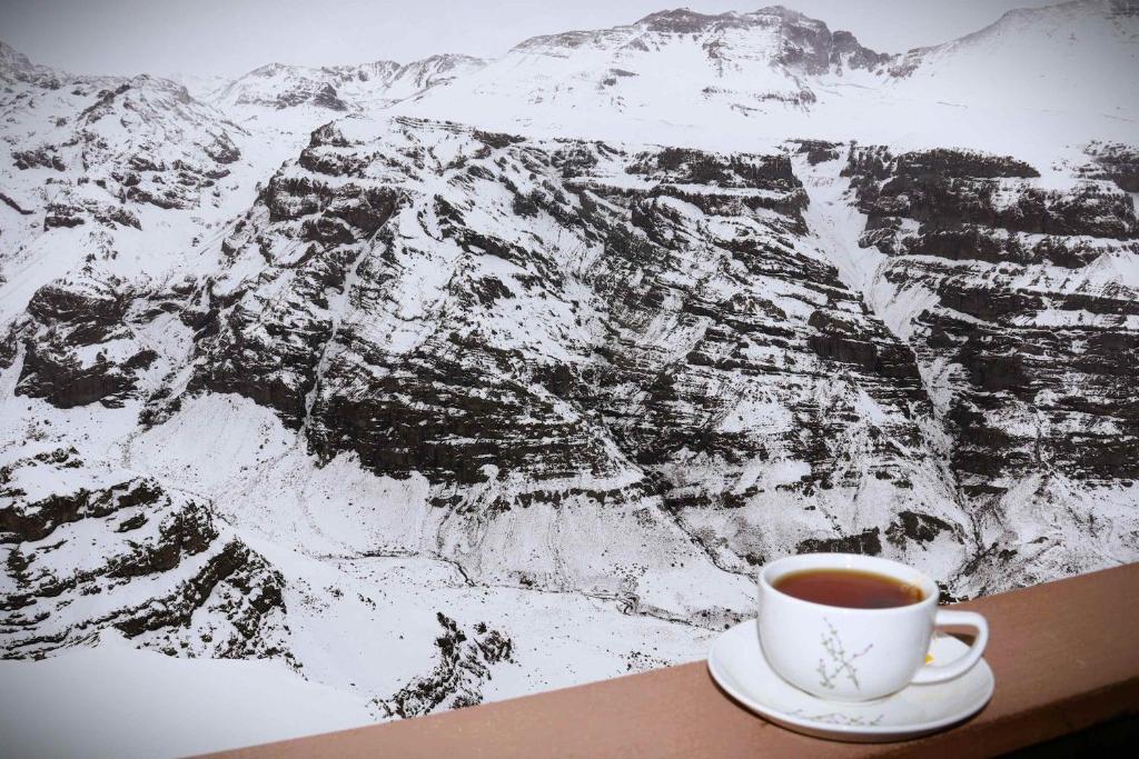 a cup of coffee sitting on a table in front of a mountain at HOM I Departamento en Valle Nevado Amplio Dúplex 6PAX SKIOUT in Farellones