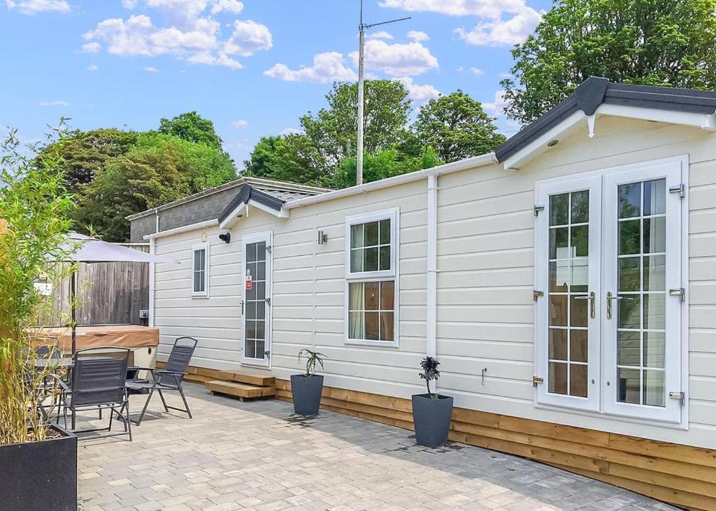 a white cabin with a patio and a table and chairs at Stream Valley Holiday Park in Penzance