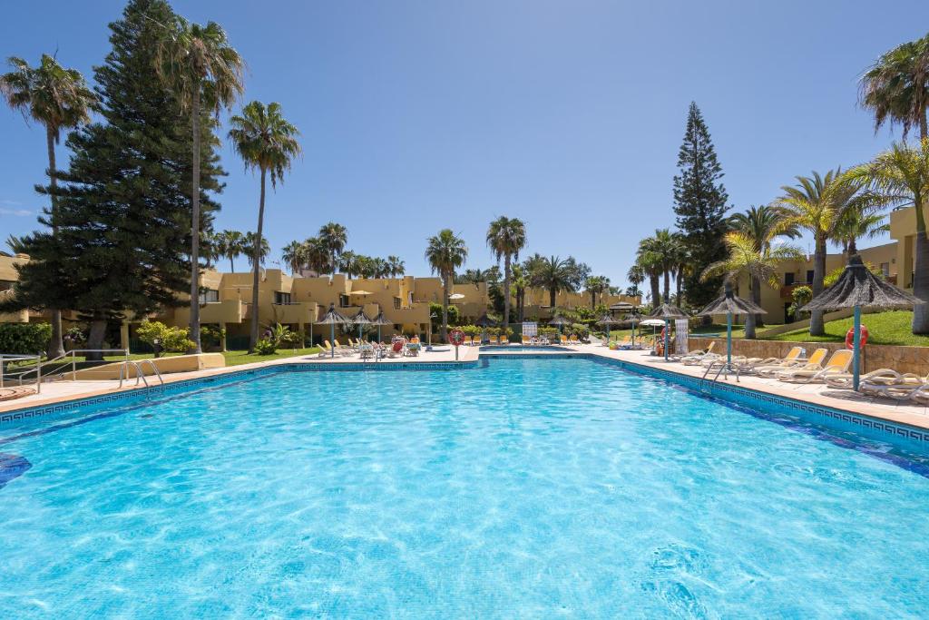ein Swimmingpool in einem Resort mit Palmen in der Unterkunft Home2Book Tranquil Escape Corralejo Community Pool in Corralejo