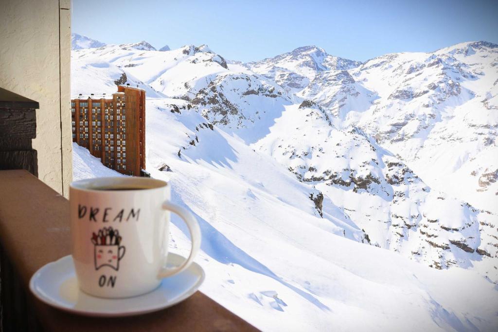 una taza de café sobre una mesa con una montaña nevada en HOM I Vc1702, en Farellones