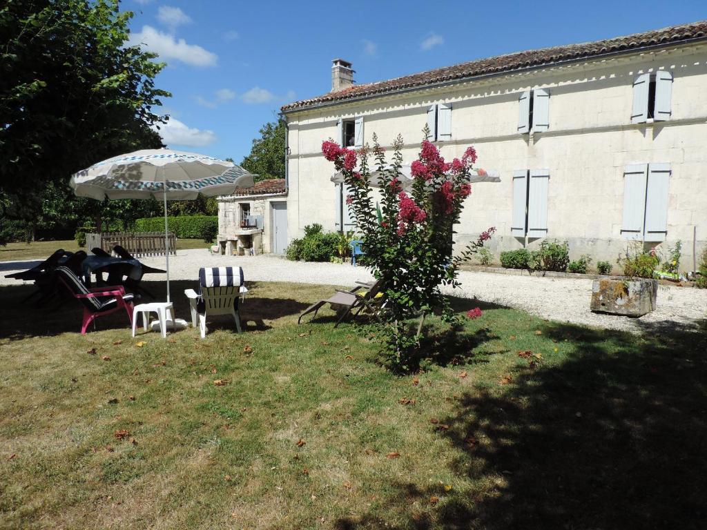 une maison avec une table et des chaises et un bush avec des fleurs roses dans l'établissement Gite Terre Océane, à Plassay