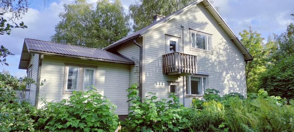 a white house with a balcony and trees at Spacious Apartment for 8 with Sauna in Sievi