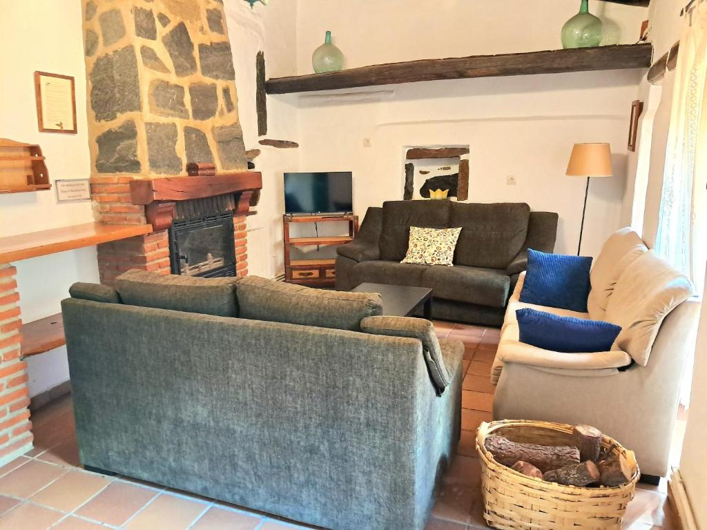 sala de estar con 2 sofás y chimenea en El Jiniebro Turismo Rural, en Valencia de Alcántara