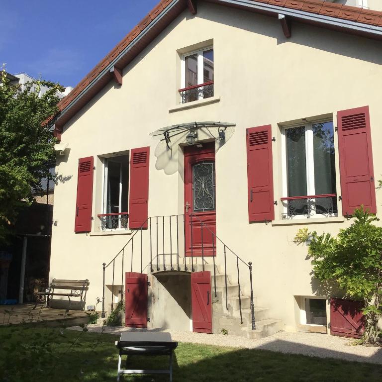 une maison avec des fenêtres à volets rouges et une porte dans l'établissement Maison Alfortville, à Alfortville