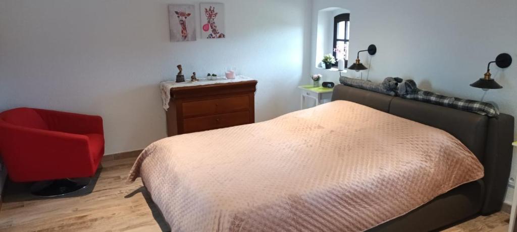 une chambre avec un lit et une chaise rouge dans l'établissement Charme authentique au coeur de saint victor malcap, à Saint-Victor-de-Malcap