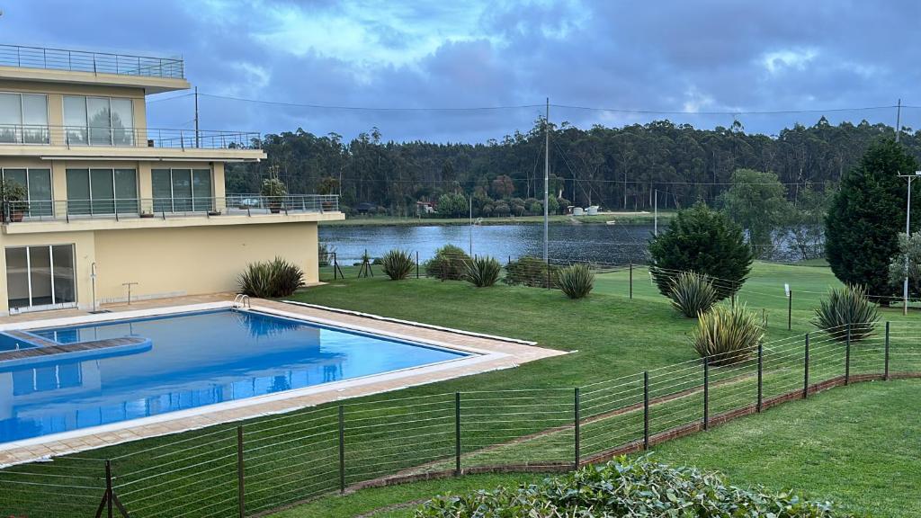 a house with a swimming pool next to a lake at Studio Luxury Quinta da Barca in Esposende