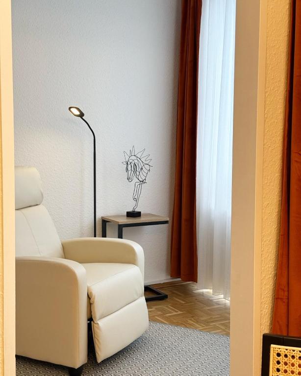 a living room with a white chair and a lamp at Seniorenresidenz am Tibusplatz in Münster