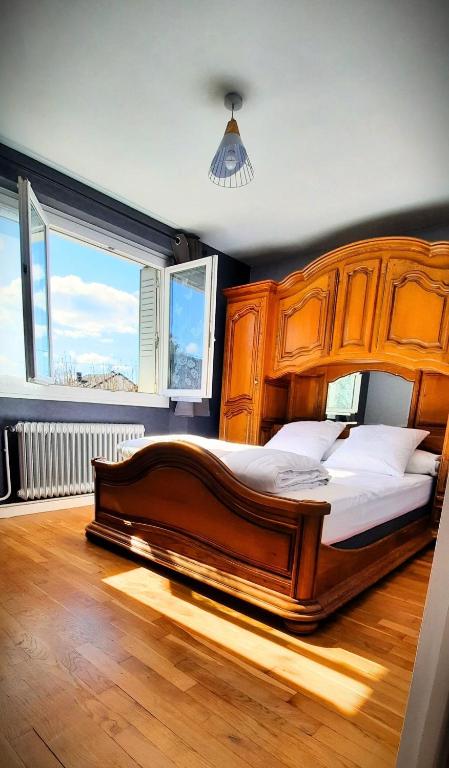 - un grand lit en bois dans une chambre avec fenêtre dans l'établissement La perle du Jura, à Champagnole