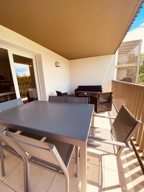 d'une table à manger et de chaises sur un balcon. dans l'établissement Apt clim 4 p clim avec piscine et parking 400 m plages- V0775, à Vias