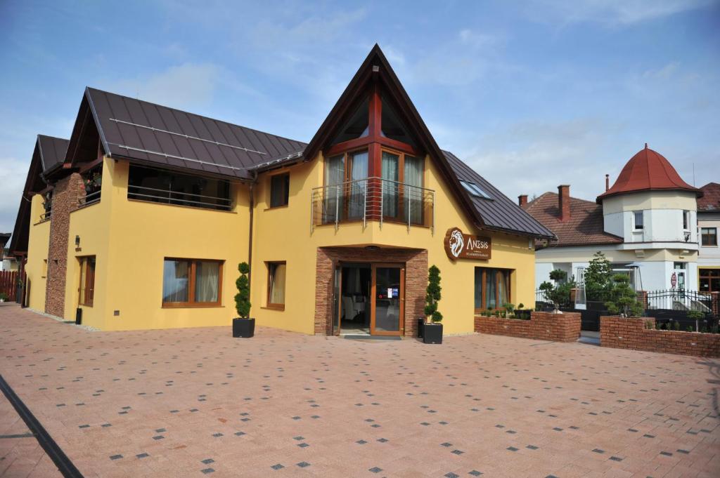 a yellow building with a black roof at Penzion Anesis - štúdiá in Turčianske Teplice