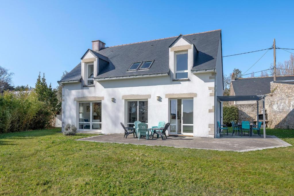 a white house with tables and chairs in the yard at A 150m de la plage, jolie maison avec jardin pour 10 in Saint-Sébastien
