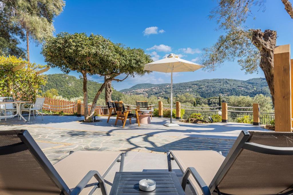 a patio with a table and chairs and an umbrella at Villa Angelo ΙΙ in Paleokastritsa