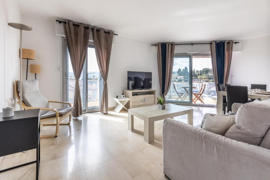 un salon avec un canapé et une télévision dans l'établissement LB Vacation Rentals I High Floor Sea View 2Br Apt with Balcony & Garage, à Cannes
