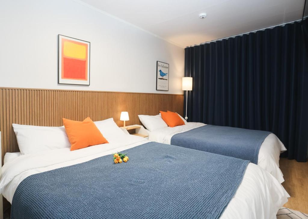 two beds in a hotel room with orange and blue at 상왕십리역3분#미니영화관#층전체#동대문#명동#홍대#종로#성수#서울숲#한양대#청계천#공항버스 in Seoul