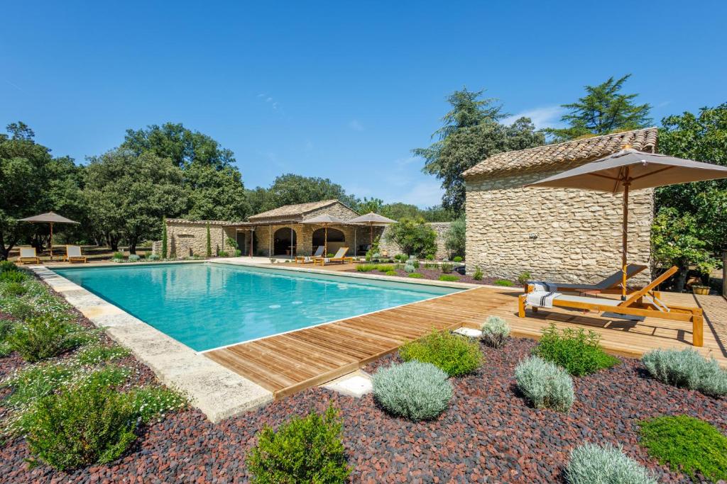 une piscine avec une terrasse en bois et un bâtiment dans l'établissement Ô Mas de Mèze, à Uzès