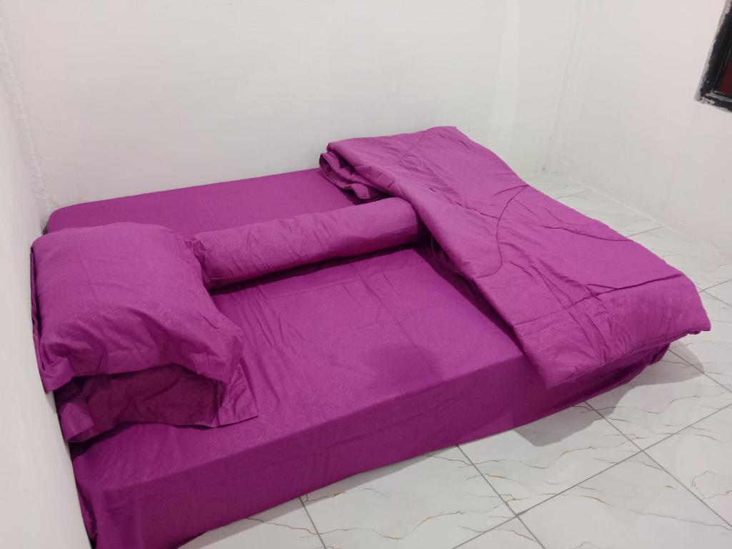 Cama morada en la parte superior de una habitación en Homestay komodo, en Komodo