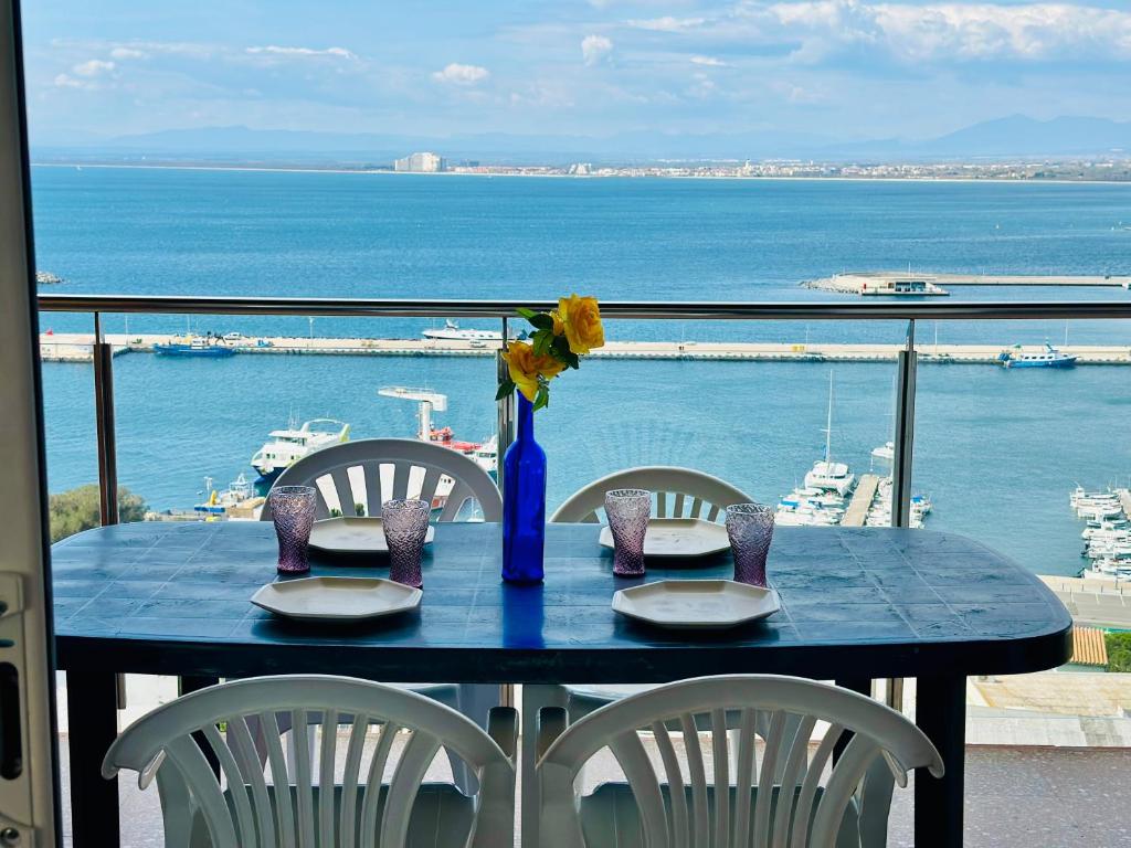 ein Tisch mit Stühlen und einer blauen Vase mit Blumen darauf in der Unterkunft Global Immo 3017 Monaco in Roses