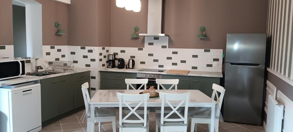une cuisine avec une table, des chaises et un réfrigérateur dans l'établissement Gîte la pause picarde, à Franleu