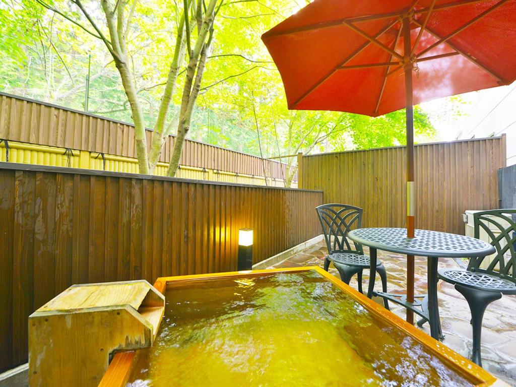 a hot tub with a table and chairs and an umbrella at Hotel Euro City in Nikko