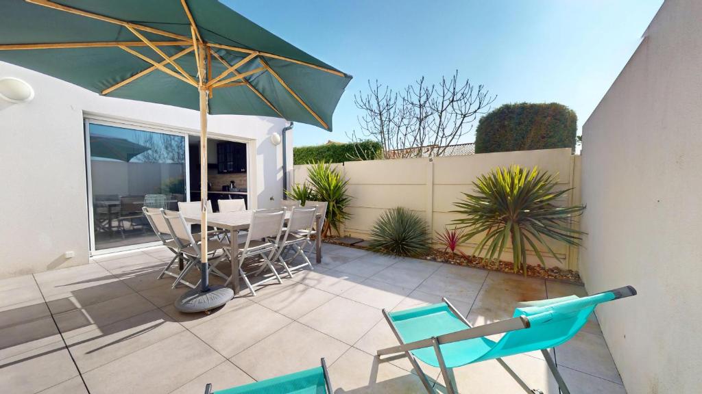 eine Terrasse mit Tisch, Stühlen und Sonnenschirm in der Unterkunft Grain de Vie - Belle maison proche plage in Saint-Gilles-Croix-de-Vie