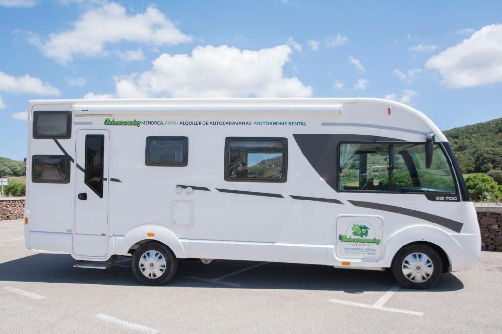 a white camper van parked in a parking lot at Autocaravaning Menorca in Ferreries