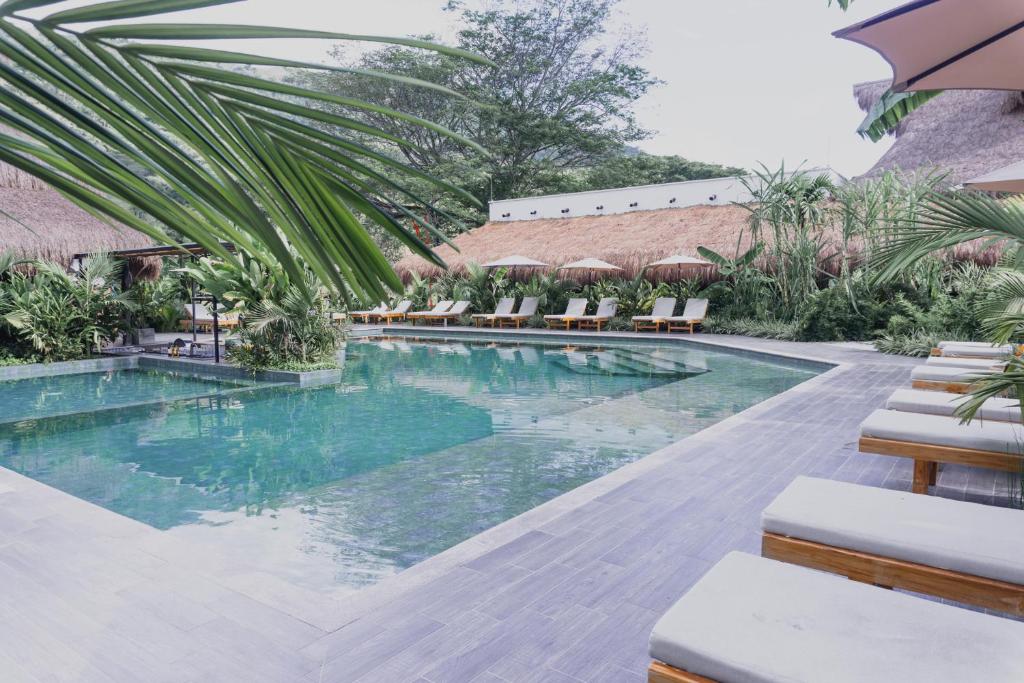 a pool at a resort with chairs and trees at Anzalik Hotel Boutique in Anzá