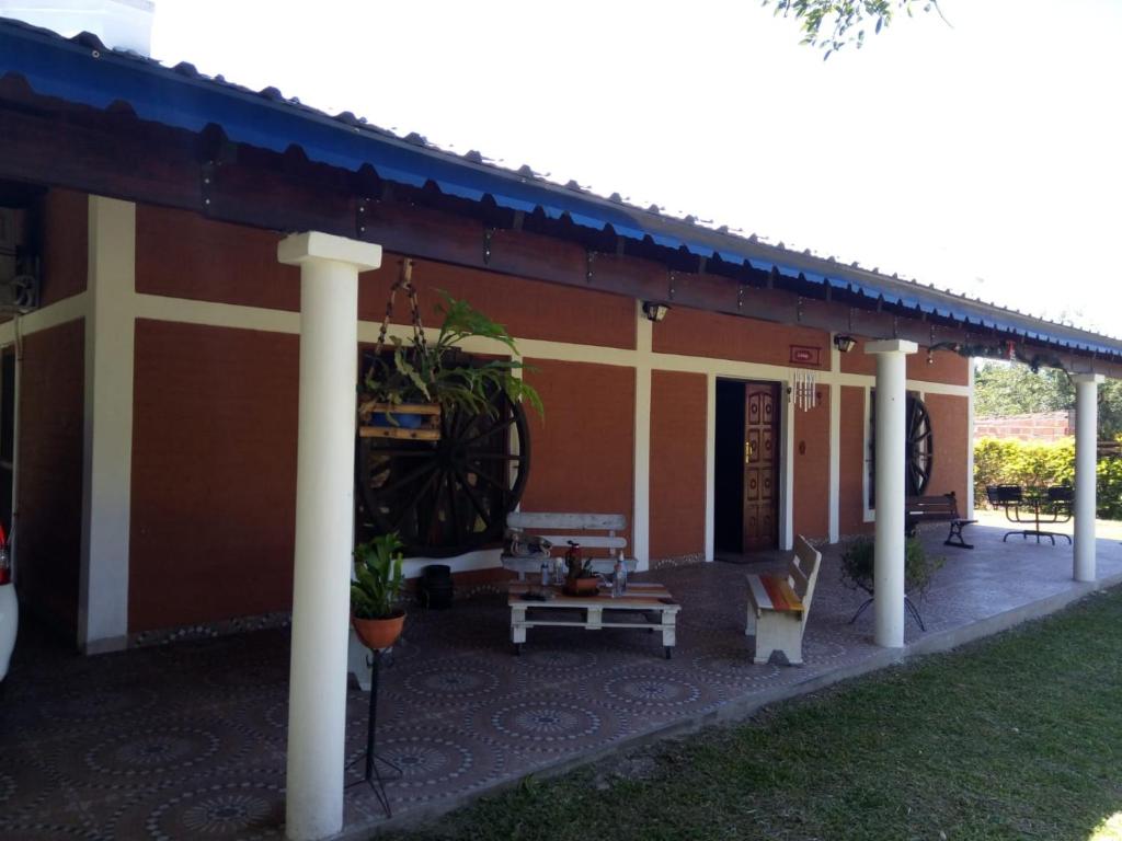 a building with a porch with a bench and a table at Peñemboha Katu in Estación Colonia Carolina