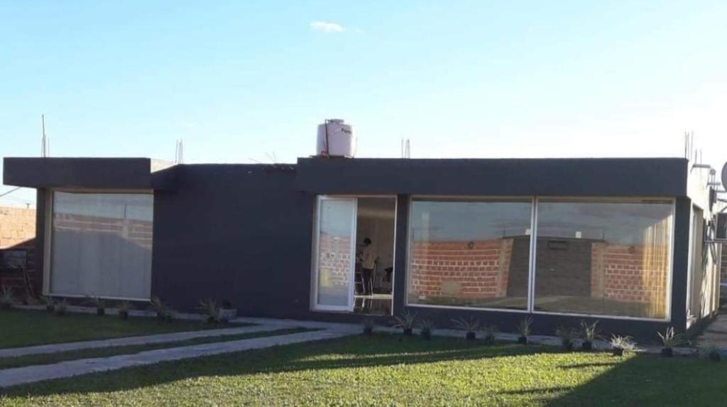 a black building with large windows in the grass at Hermosa Casa Alquiler Temporario in Corrientes