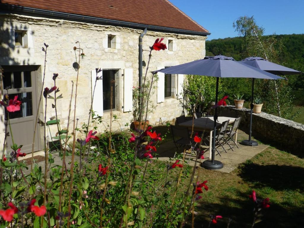 une maison avec une table, un parasol et des fleurs dans l'établissement Vialard, à Salignac Eyvigues