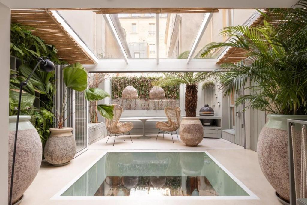 une véranda avec une piscine au milieu d'une pièce ornée de plantes dans l'établissement La Baraka, à Paris