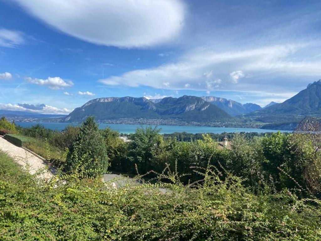 une vue d'un lac avec des montagnes en arrière-plan dans l'établissement St-Jorioz Maison vue lac et montagnes 6pers, à Saint-Jorioz