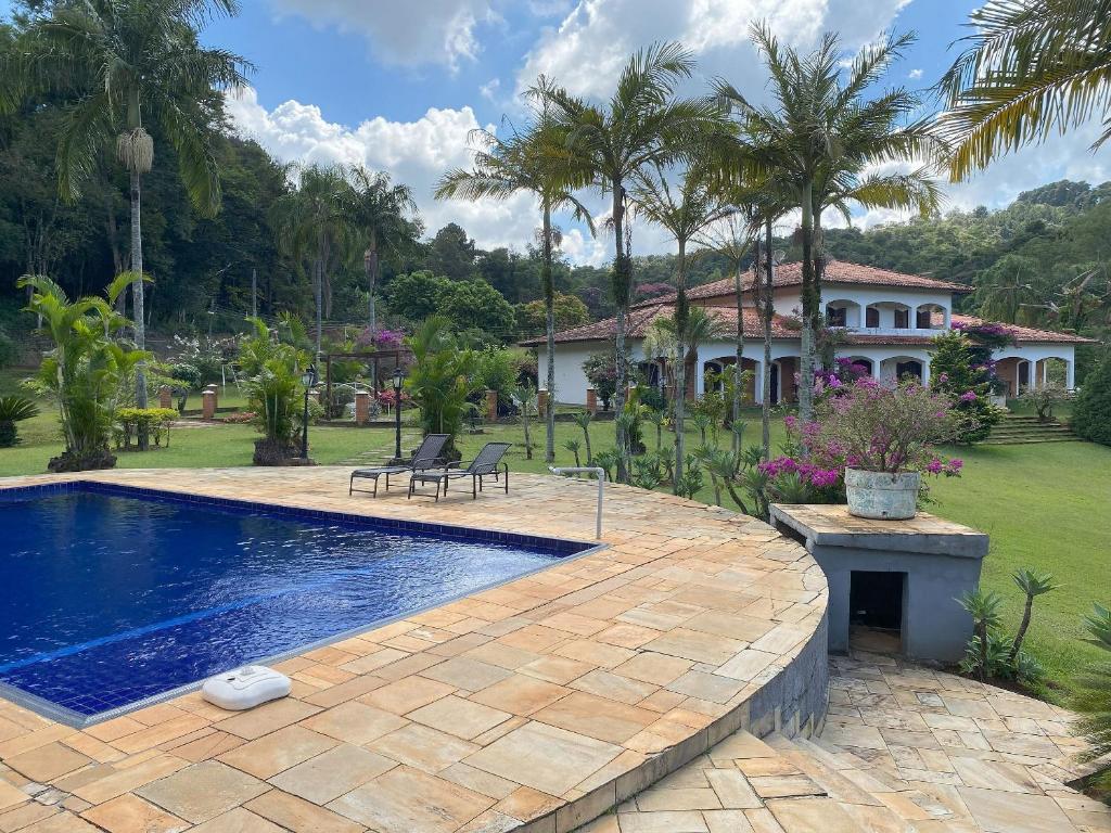 a swimming pool in front of a house with palm trees at Espaço Eslovaquia - Casarão com Piscina, Paz e Conexão com a Natureza in Atibaia