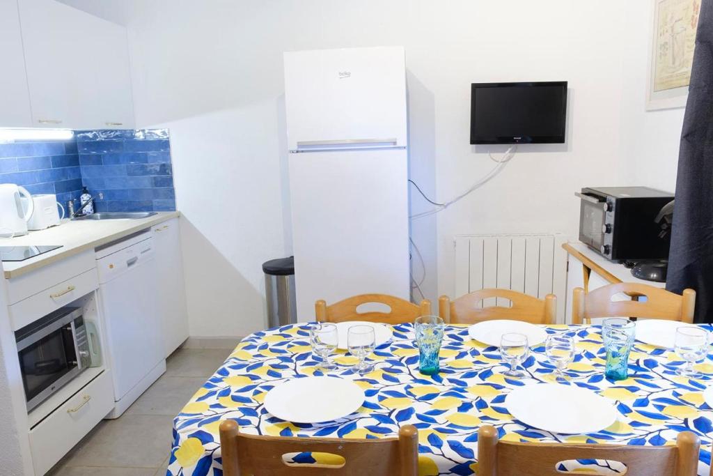 Il comprend une cuisine équipée d'une table avec des chaises et d'un réfrigérateur blanc. dans l'établissement Beautiful apartment with pool in Sainte-Maxime, à Sainte-Maxime
