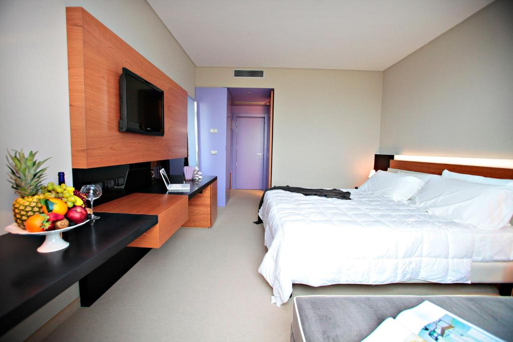 チヴィタノーヴァ・マルケにあるCosmopolitan Hotelのベッド1台とフルーツ1杯が備わるホテルルームです。