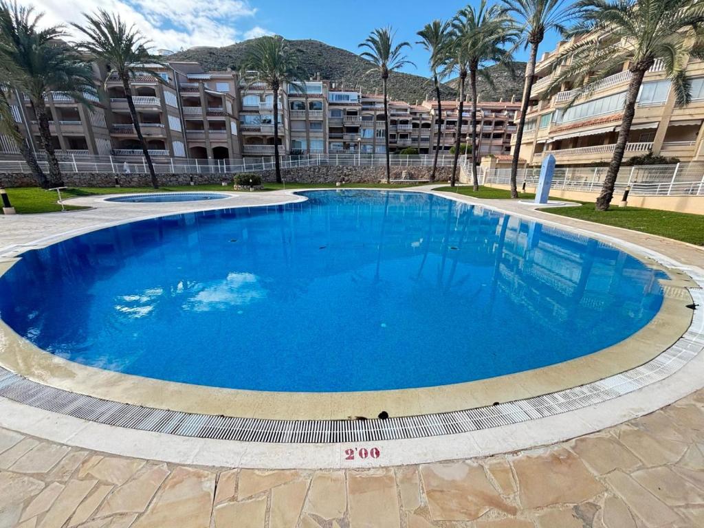 a large blue swimming pool in front of a building at Bahia Park Résidence in Cullera