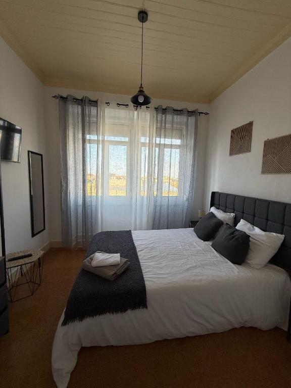 a bedroom with a large bed with a large window at Casa das Muralhas in Peniche