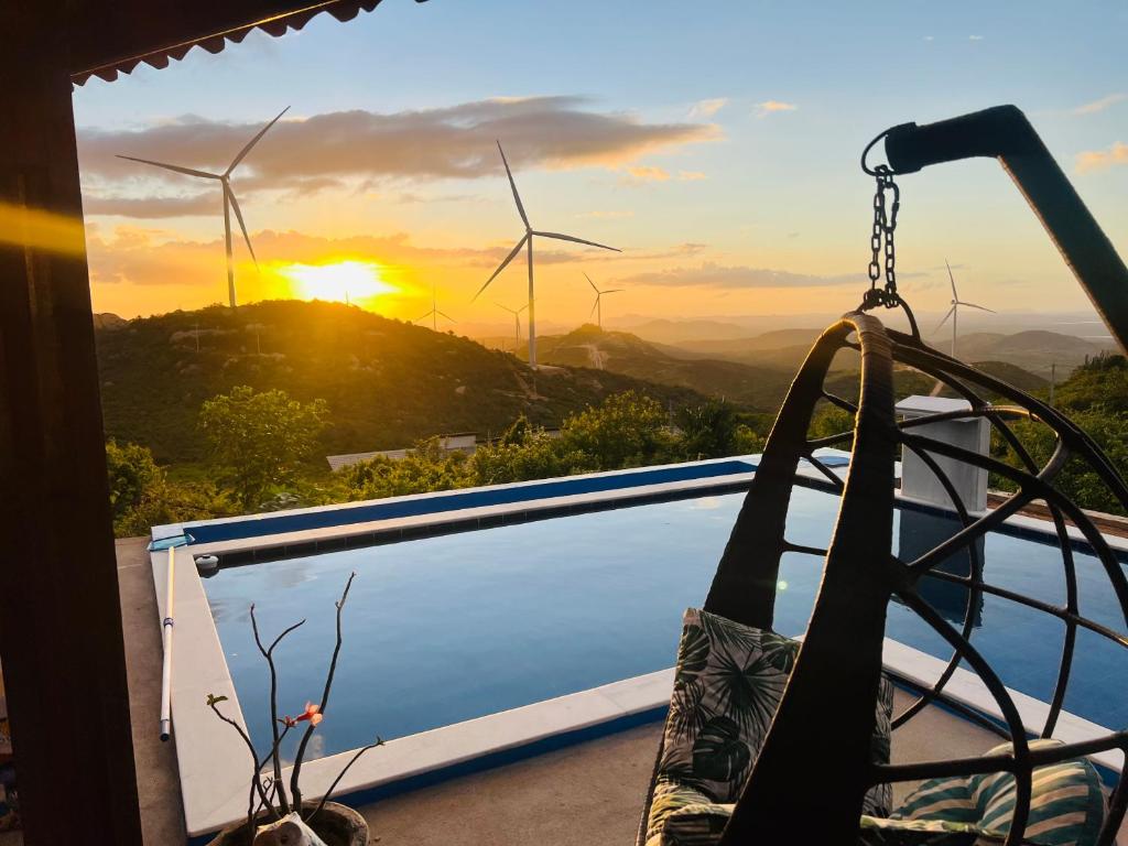 einen Pool mit Sonnenuntergang und Windmühlen im Hintergrund in der Unterkunft Margarida 03 in Monte das Gameleiras