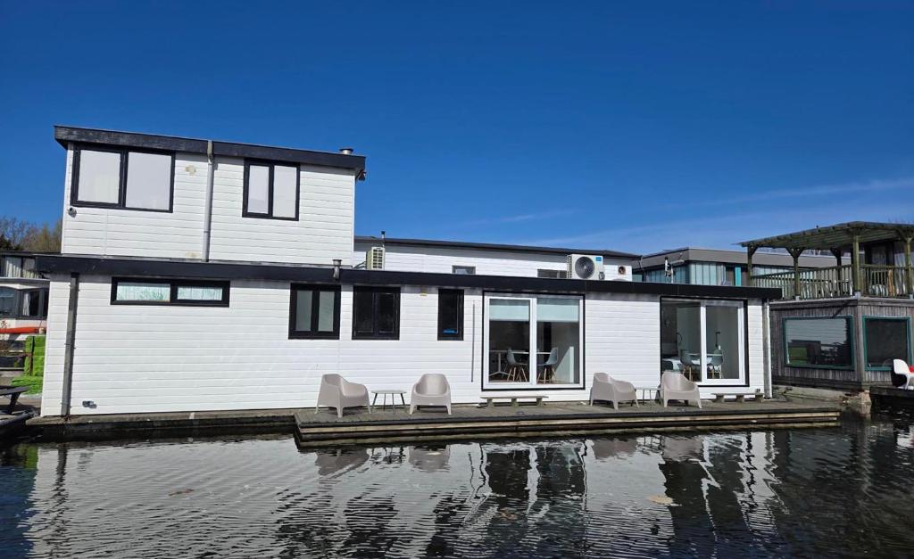una casa su un molo con sedie sull'acqua di HouseBoat the New Lake - Nieuwe Meer ad Amsterdam