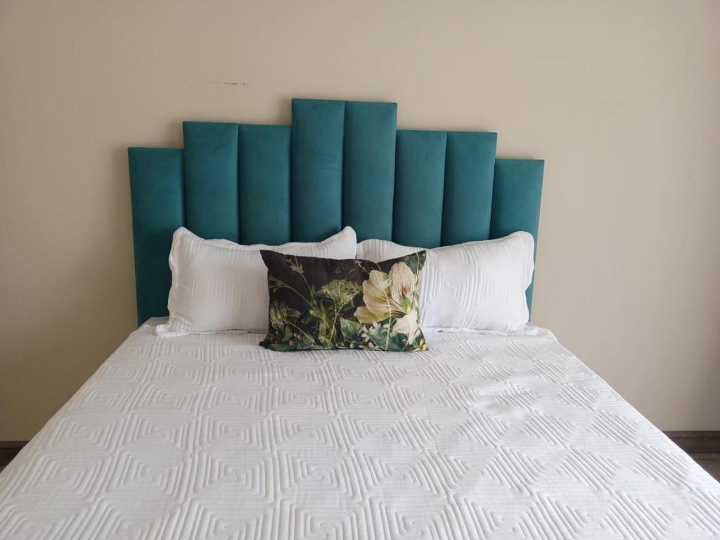 a large bed with a blue headboard and pillows at 04 at Beaumont in King Williamʼs Town