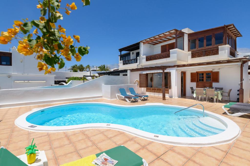 a villa with a swimming pool in front of a house at VILLA ERIC with a private stunning heated pool in Puerto del Carmen