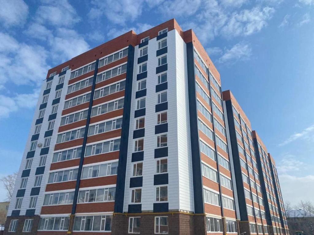 a tall office building with a sky in the background at Уютные апартаменты в новом жилом комплексе in Kostanay