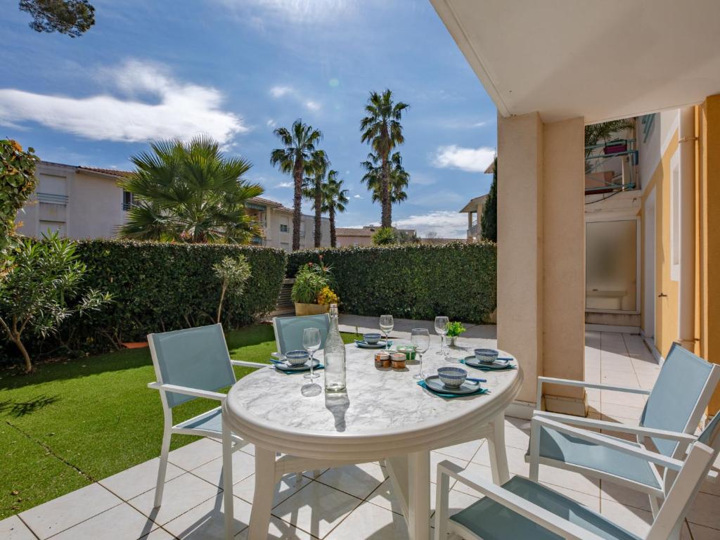 Un patio con una mesa y sillas blancas. en Apartment Le Clos Saint Saens-5 by Interhome, en Saint-Aygulf