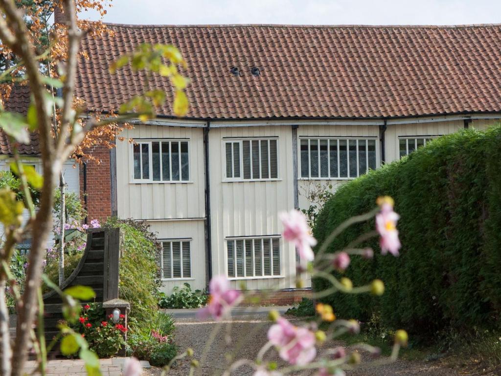 Casa blanca con techo rojo y flores rosas en Tinsmiths House en Aylsham