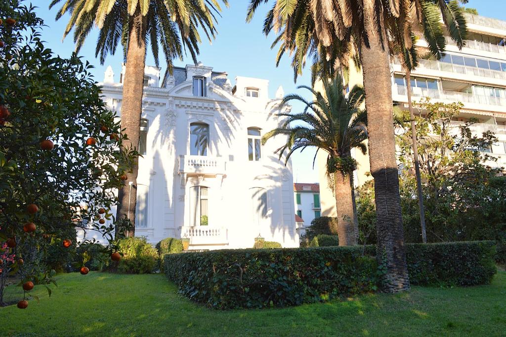une maison blanche avec des palmiers devant un bâtiment dans l'établissement Charming Apartment Cannes City Center and Beaches, à Cannes
