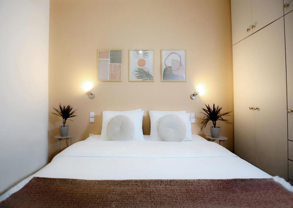 a bedroom with a large white bed with two plants at Kamena Elegance in Kamena Vourla