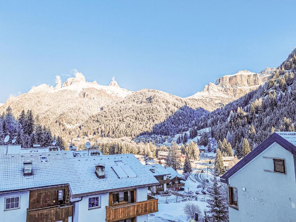 a ski resort with snow covered buildings and a mountain at Apartment Enrosadira-13 by Interhome in Alba di Canazei