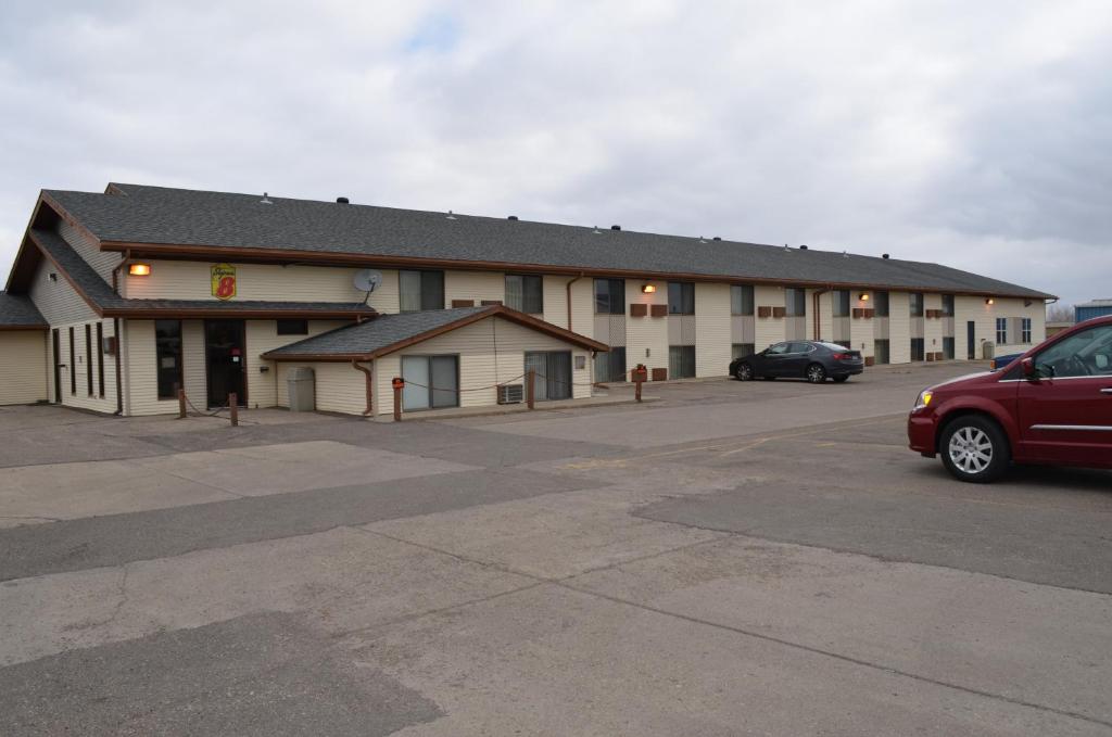 a building with a car parked in a parking lot at Super 8 by Wyndham Devils Lake in Devils Lake