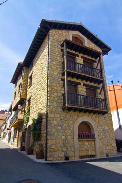 a stone building with a balcony on a street at Casa Rural El Lavadero in Bronchales