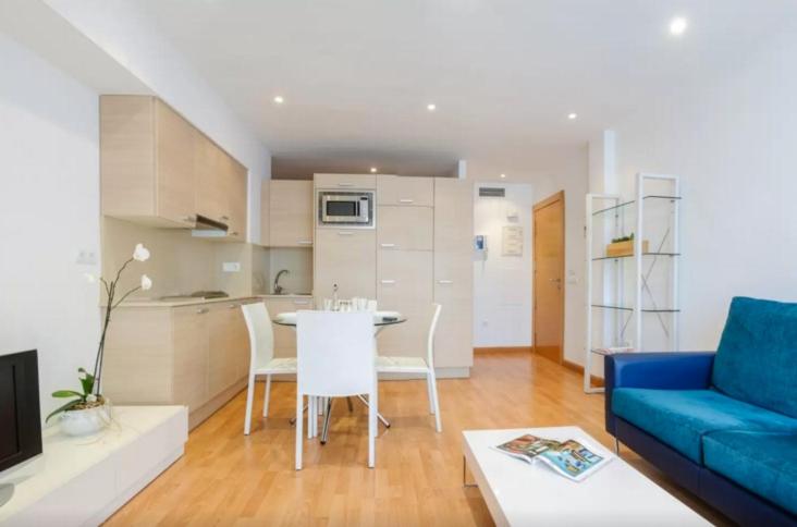 a living room with a blue couch and a table at Apartamentos La Pergola Castellón in Castellón de la Plana