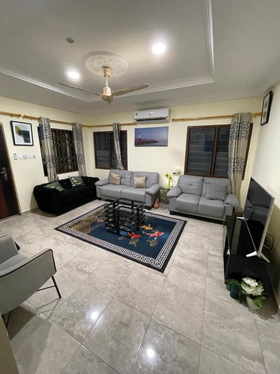a living room with couches and a tv and a couch at 2 bedroom house Accra in Apenkwa